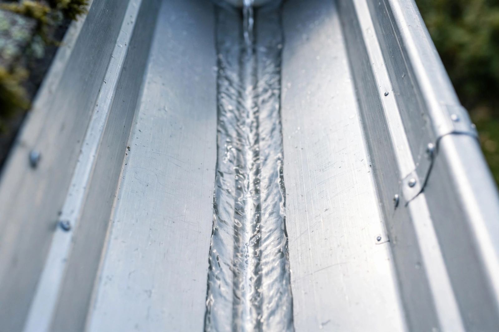 The same trough after cleaning: bare aluminum with clear flowing water